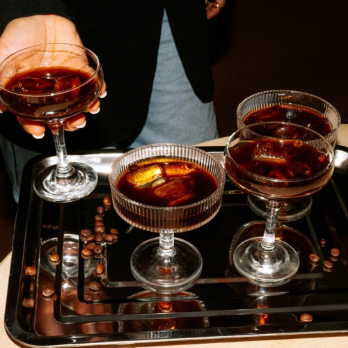 a person holding a glass with other drinks on a table