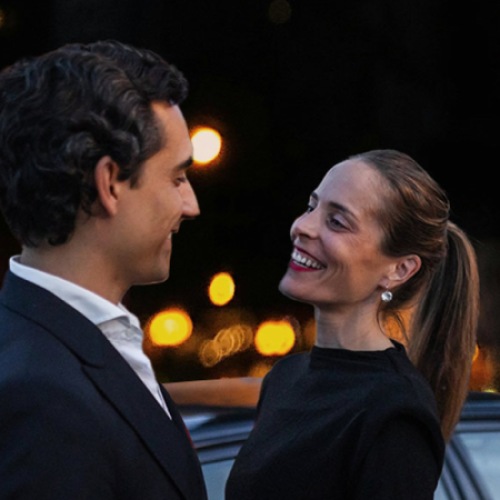 a couple smiling in front of a car